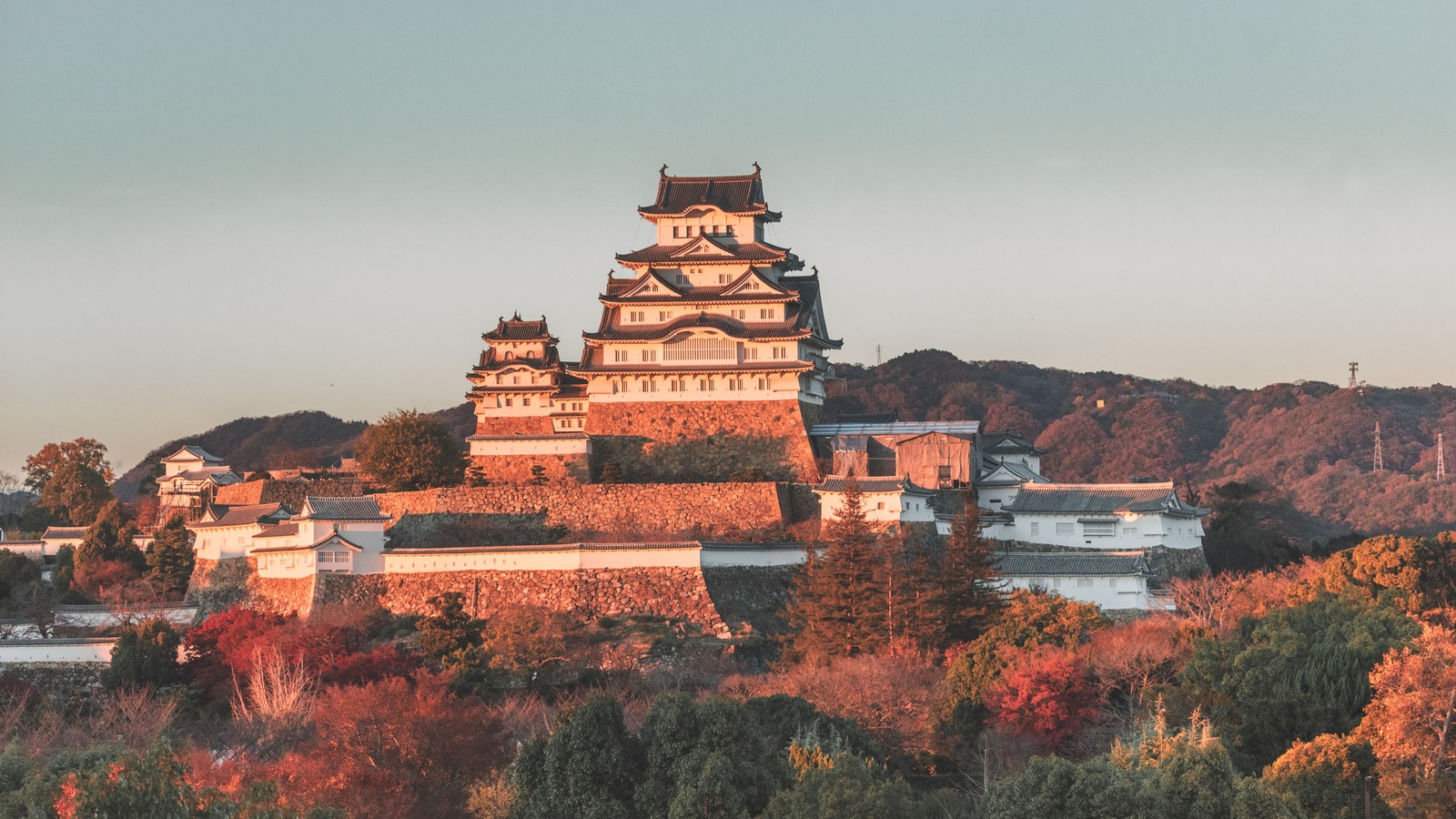 Himeji Castle in evening light with autumn foliage.